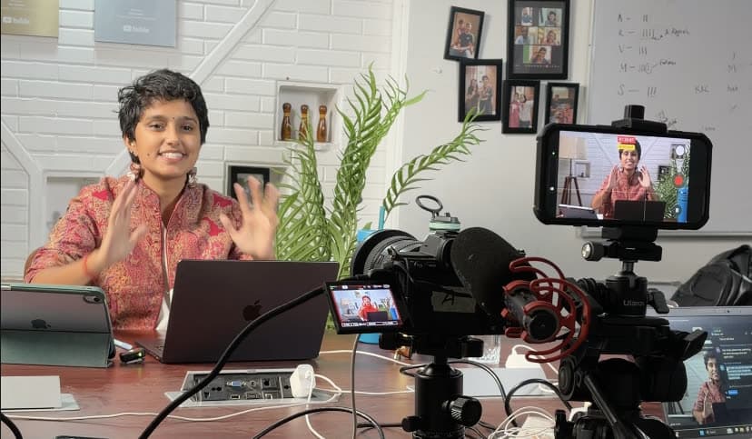 Kavya recording a piece to camera at the desk